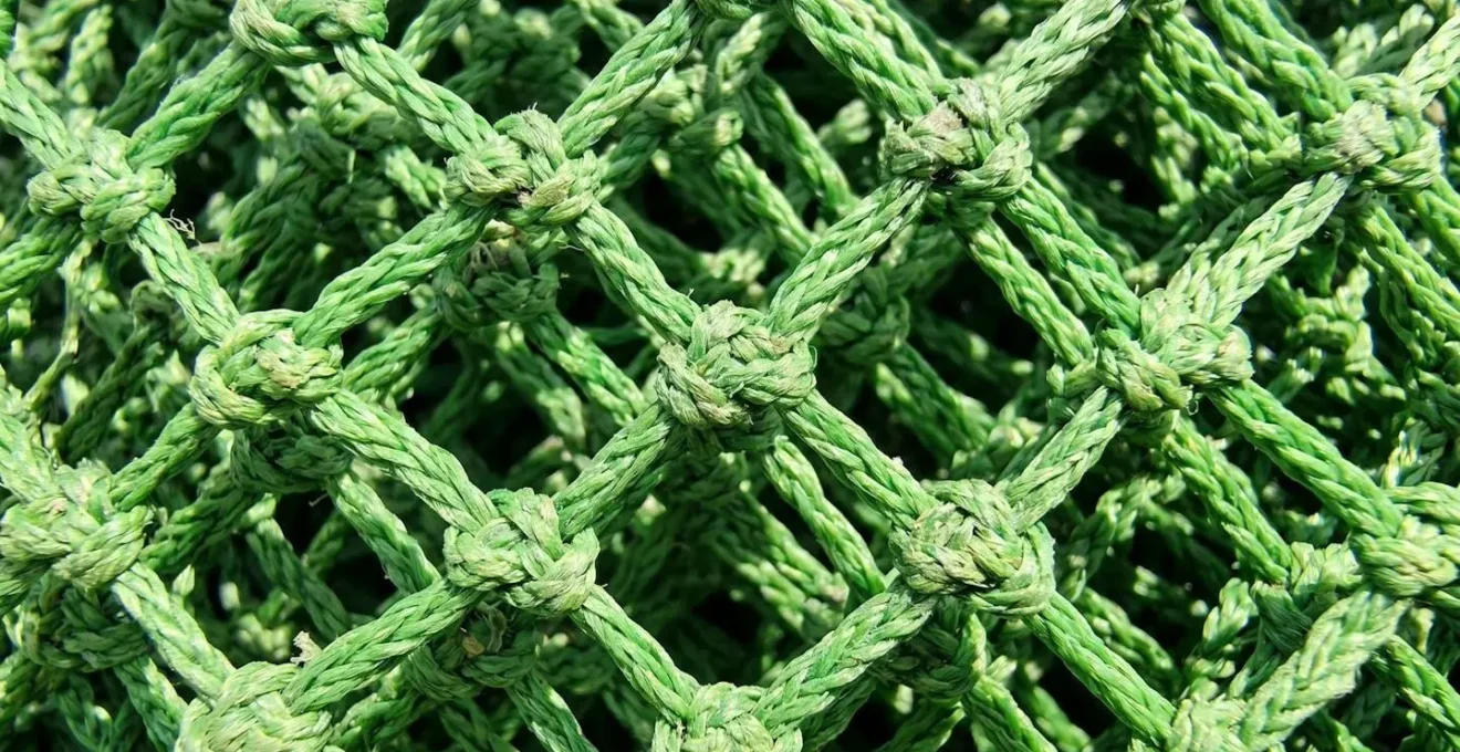 Gros plan sur la maille tressée en nylon vert d'un filet à poules montrant la finesse du tissage